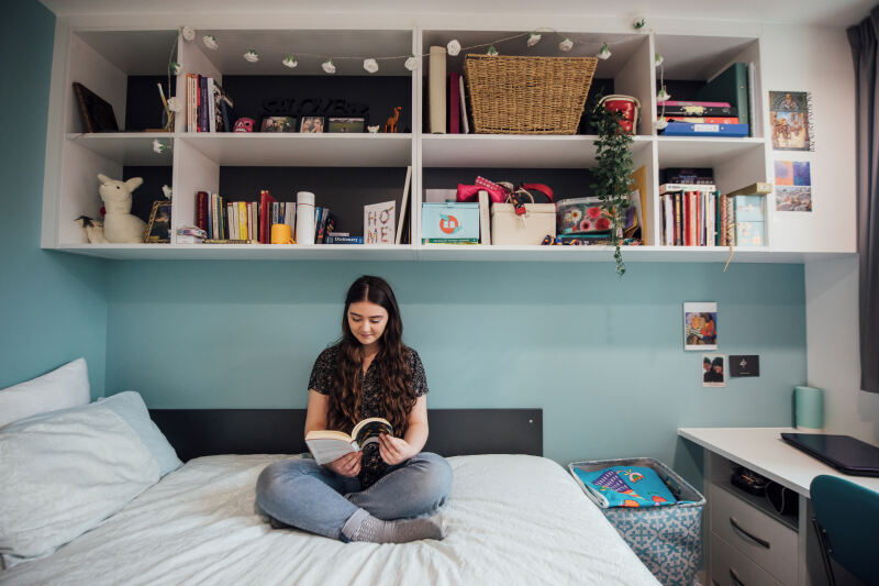 Student reading on top of bed in accommodation