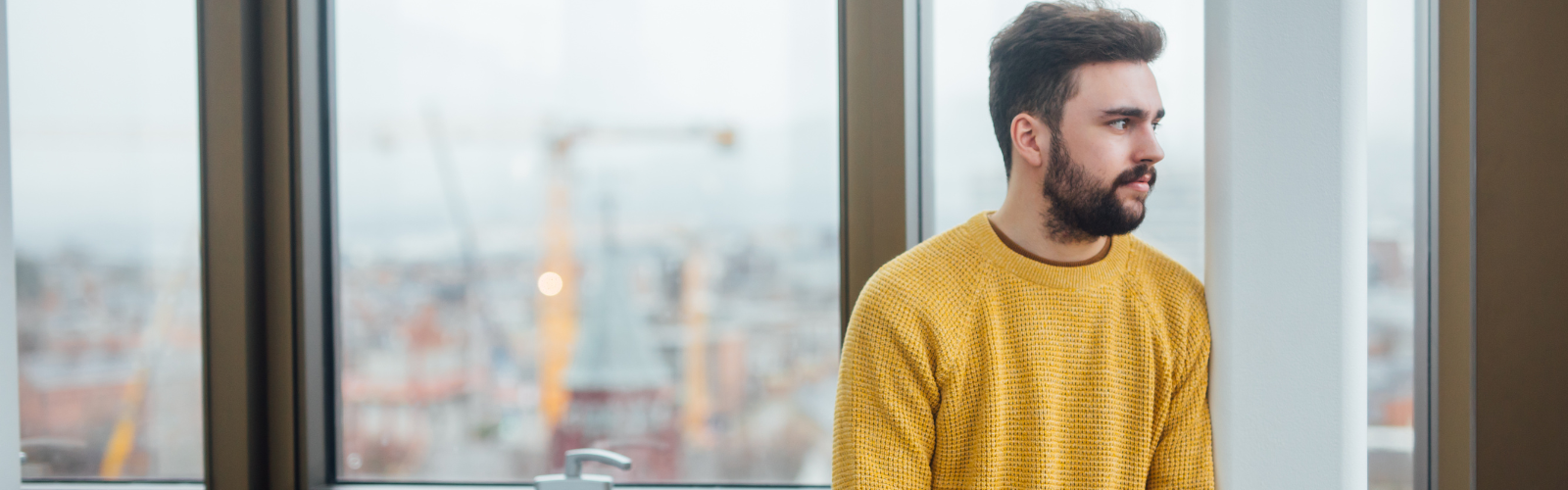 Image shows a man reflecting as he looks out the window in the Wellbeing Room, Main Site Tower.