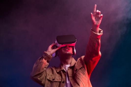 Student with VR goggles pointing upwards