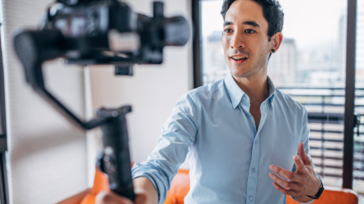 young man holding video camera to film himself