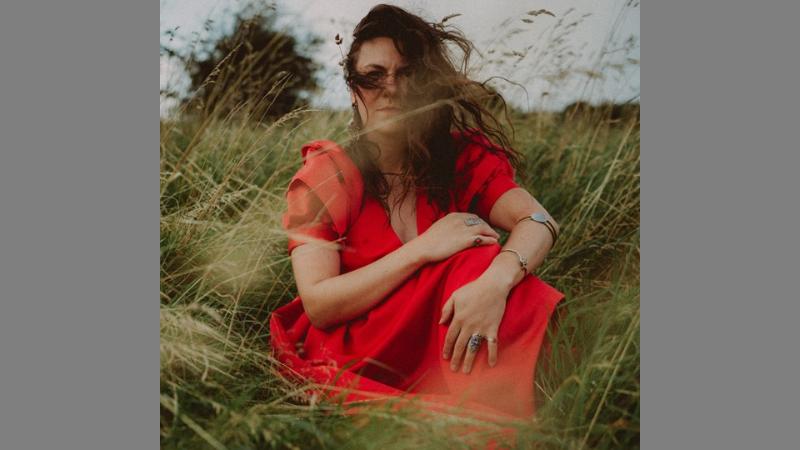 Person with long hair sitting in long grass.