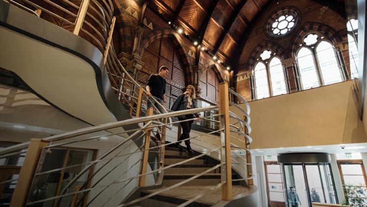 Two students walking down the steps inside the Graduate School