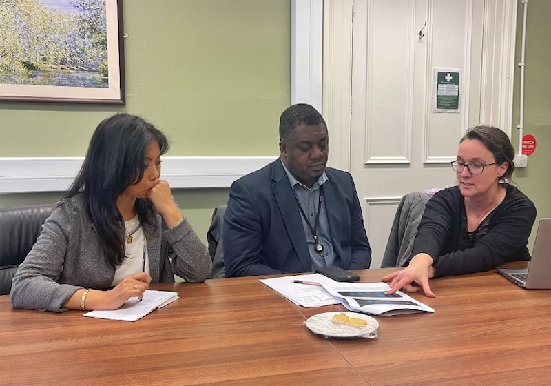 Three people examining papers at a table