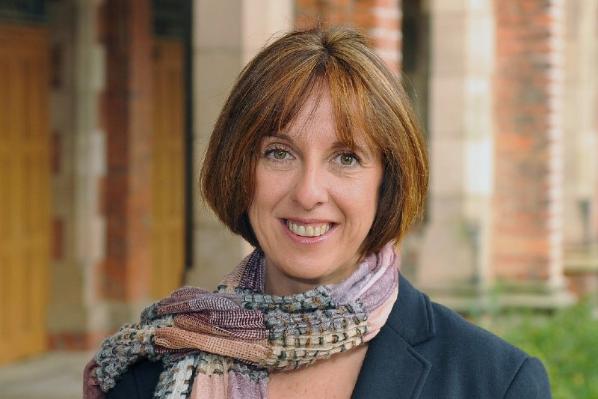 smiling woman with brown hair above shoulder length, wearing a scarf in blues and greys