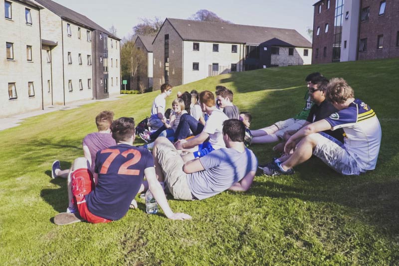 group of students sitting on grass in Elms village