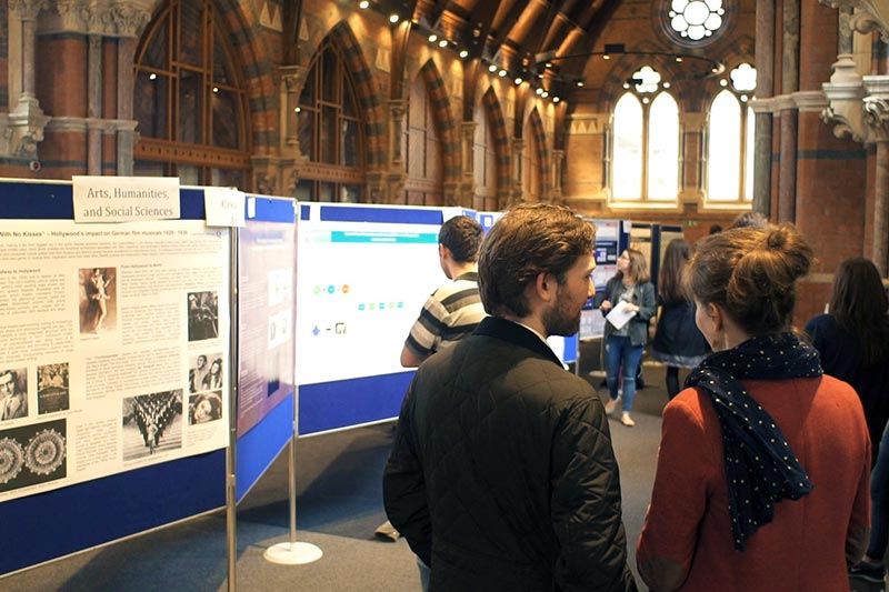 The upper floor of the Graduate school filled with multiple posters on boards and students attending a poster competition
