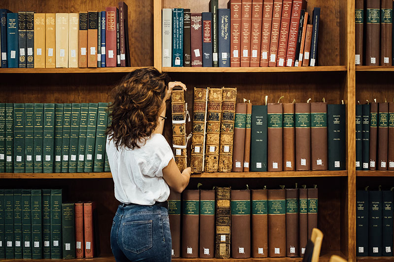 Student lifting an old book in the Special Collections room