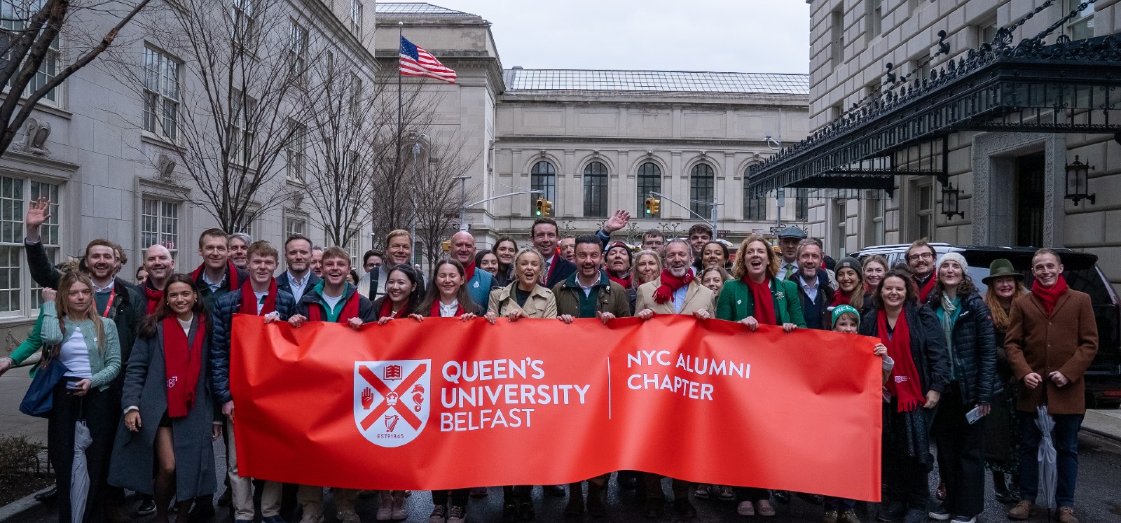 Alumni from Queen's University march in the St Patrick's Day parade in New York, 2025, holding a branded, red banner