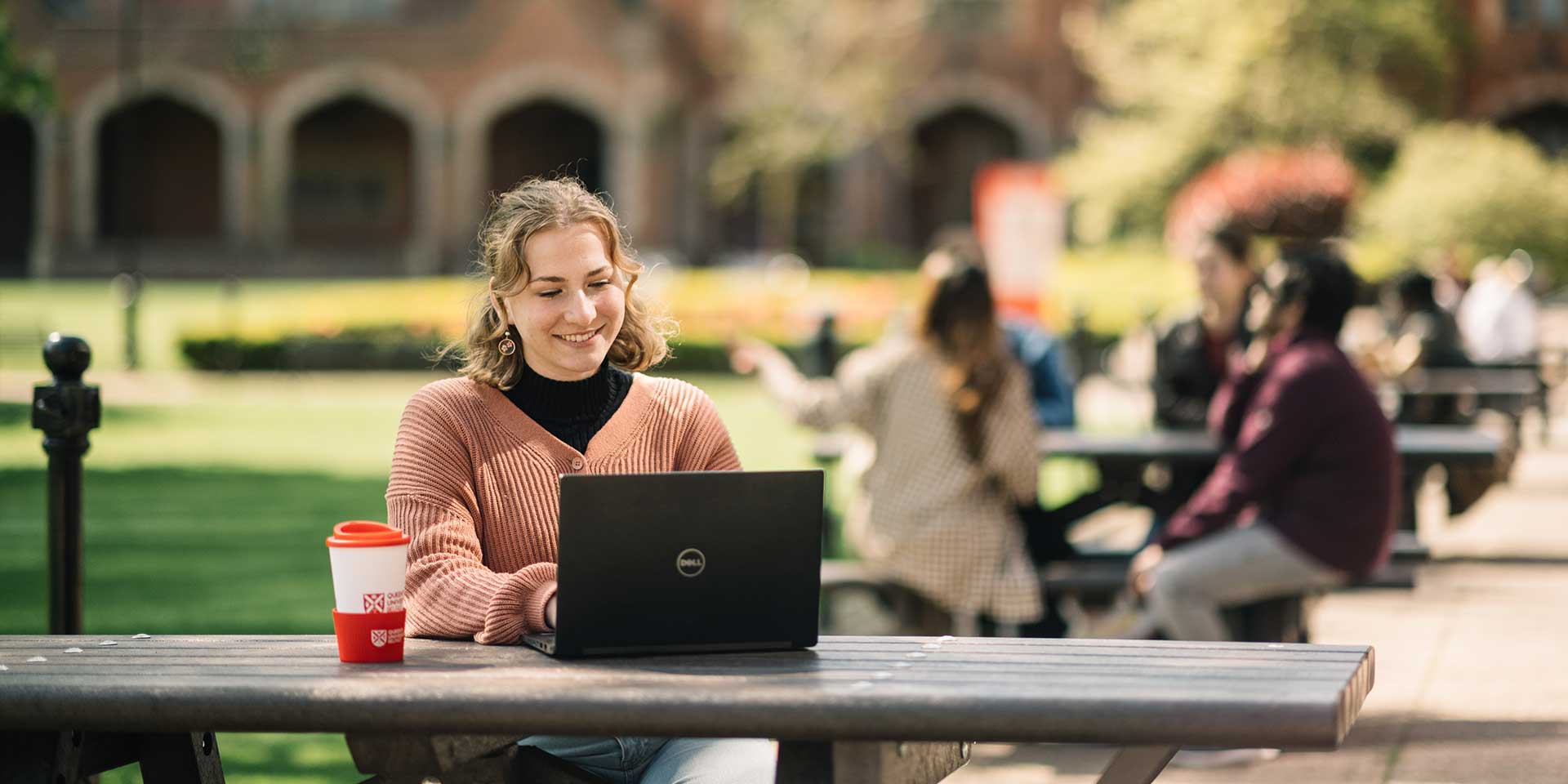 Student sitting on bench using laptop