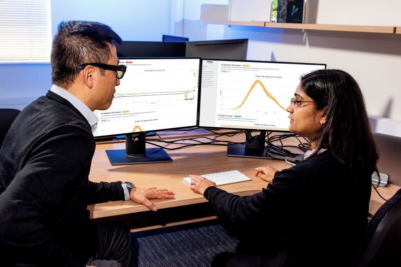 Two members of Bioinformatics staff discuss data analysis in front of computer display