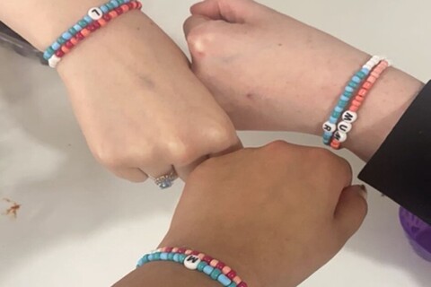 Three students making bracelets with the art society