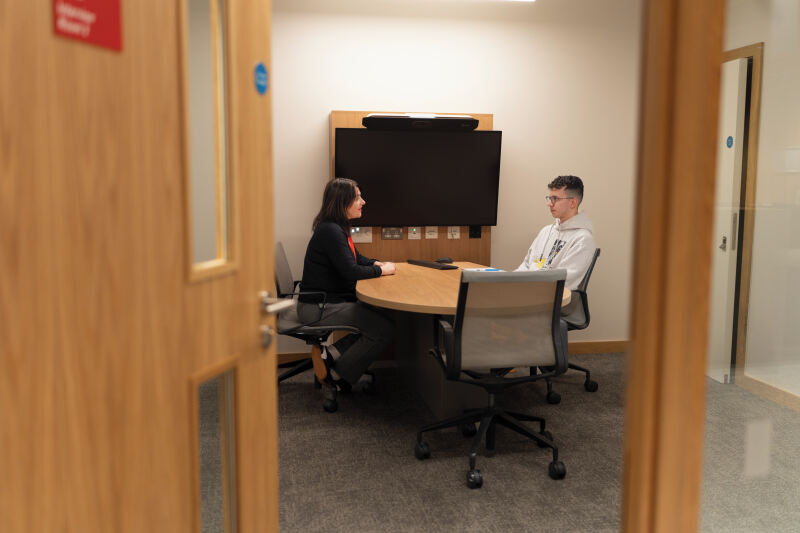 Staff and student talking in room in Queen's Business School