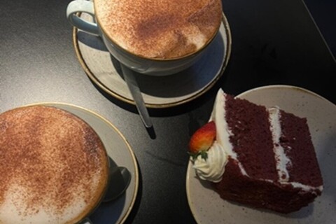 Cups of coffee and slice of cake on a plate