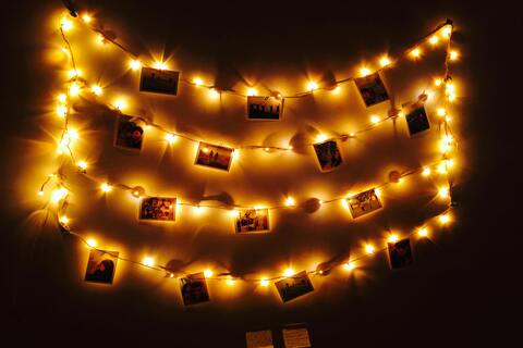 Strings of fairy lights on a wall with polaroids