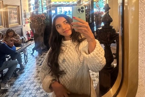 Student Isabella taking selfie in mirror inside cafe