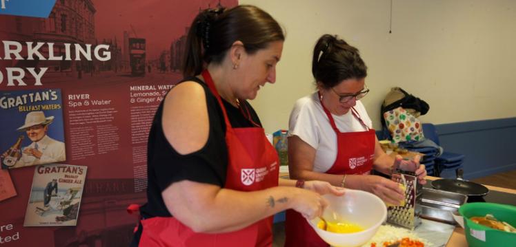 Two women preparing food looking away from camera