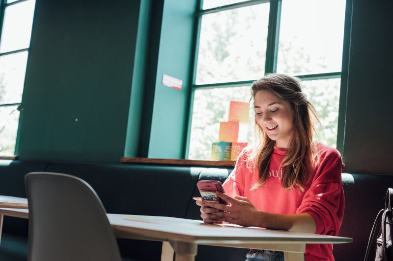 Mature student looking at phone while sitting at table