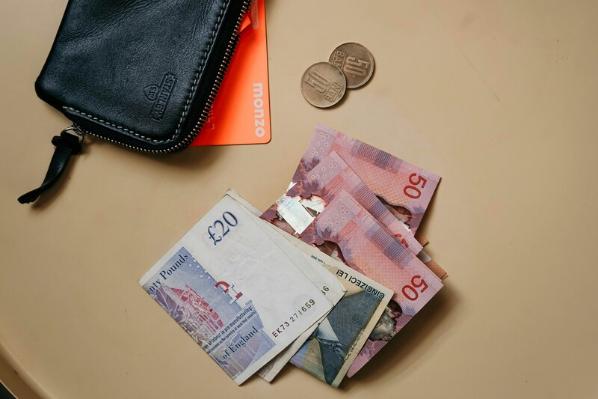 Monzo card inside wallet beside notes and change