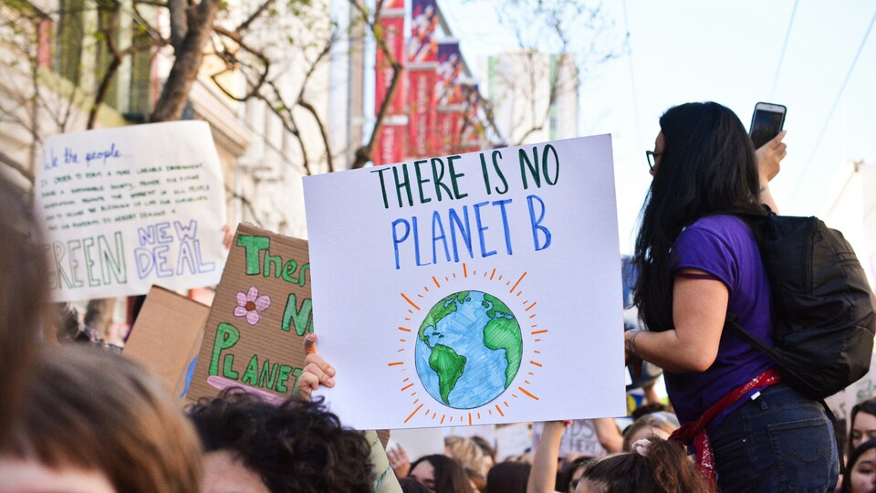 Climate change march with people holding signs saying 'There is no Planet B'