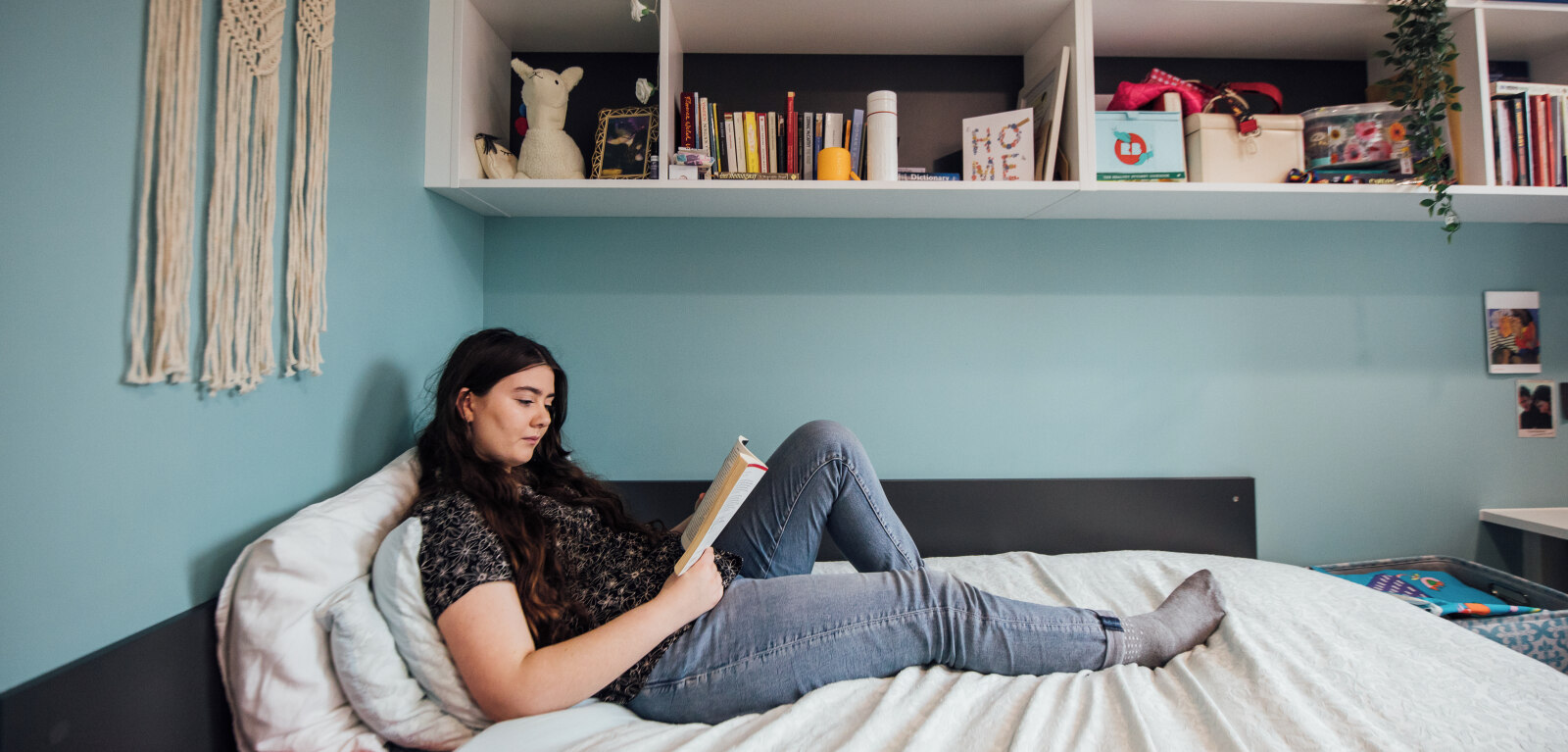 Student lounging on bed in accommodation