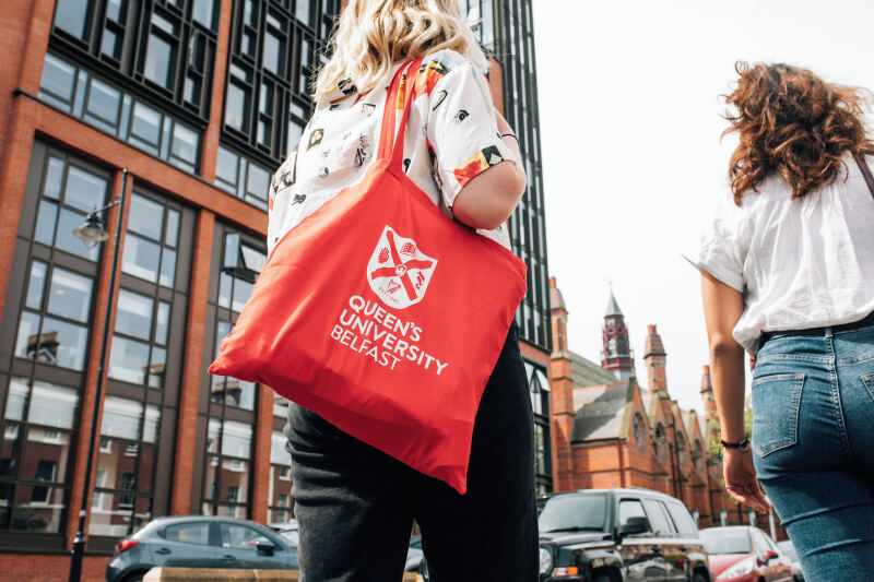 Student walking through campus with Queen's tote bag