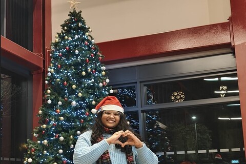 Student Sai Sree in front of Christmas tree in the SU