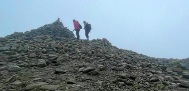 Two hikers reaching the summit of Slieve Donard