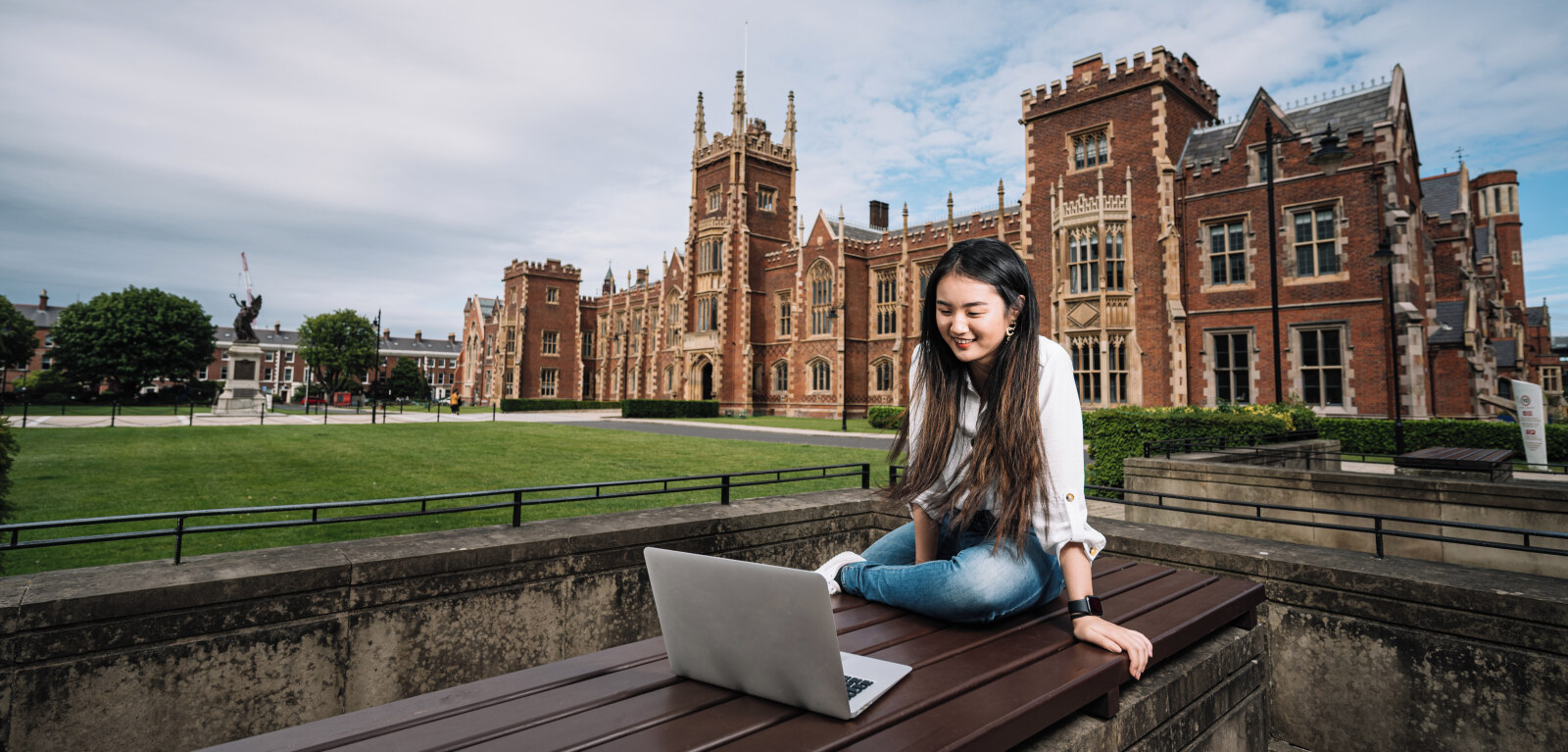 Student on laptop in front of Lanyon building