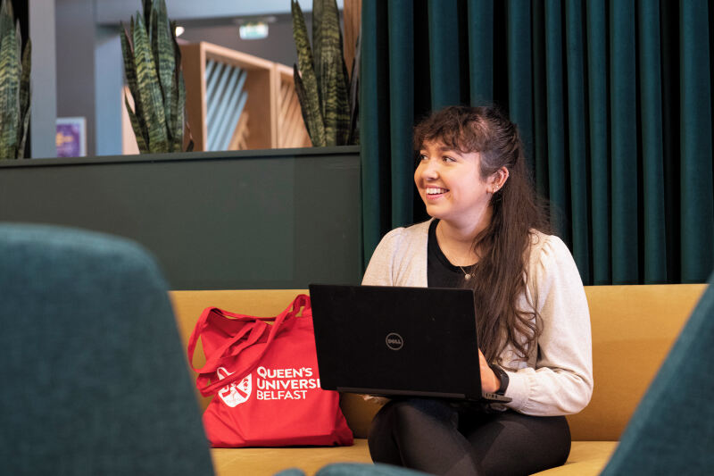 Student with laptop and Queen's tote bag