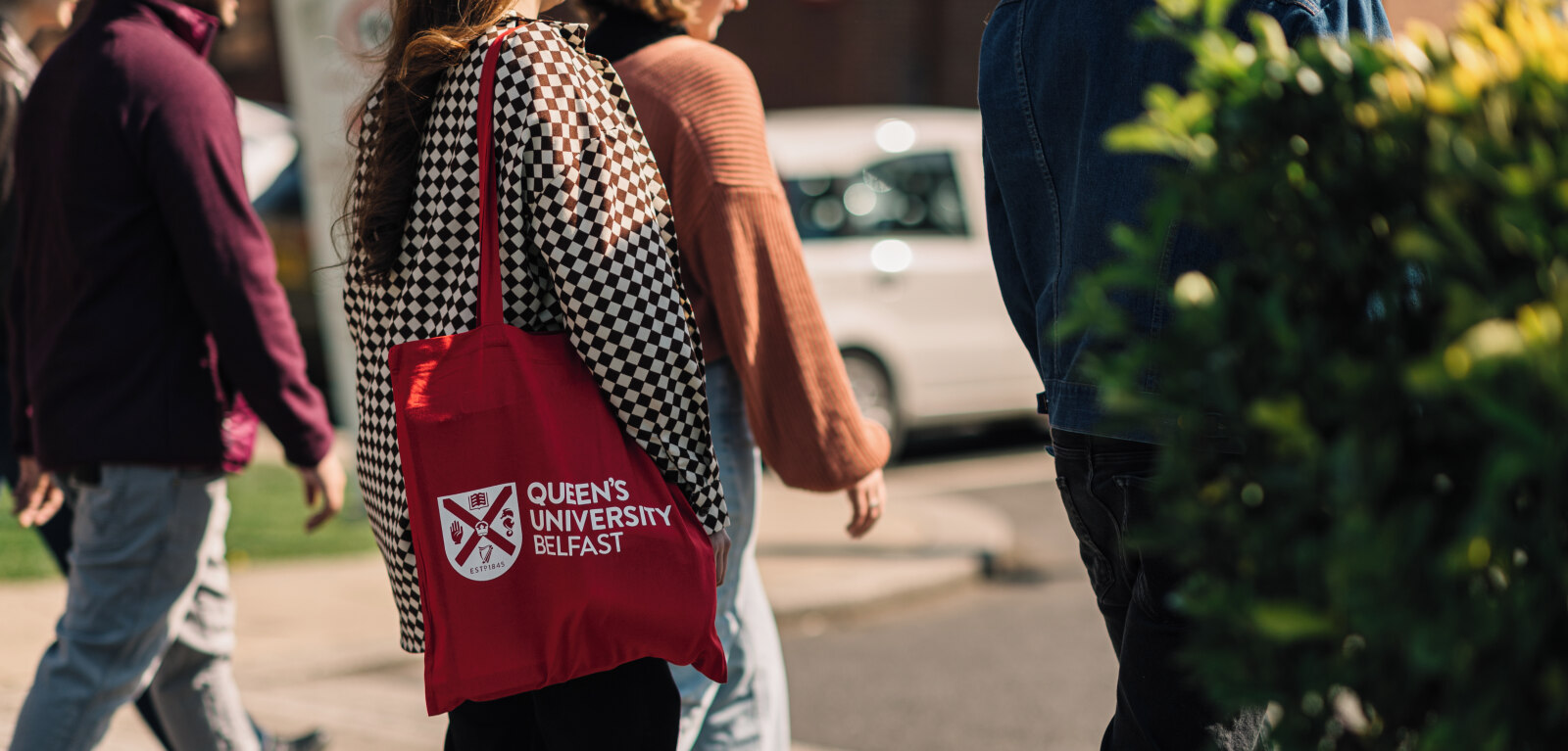 Student walking with QUB tote bag