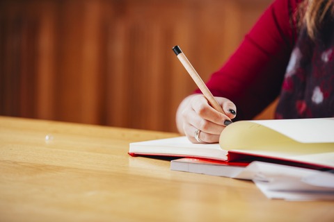 Student writing with pen on notebook