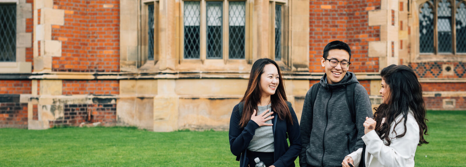 Three international students walking in front of the Lanyon