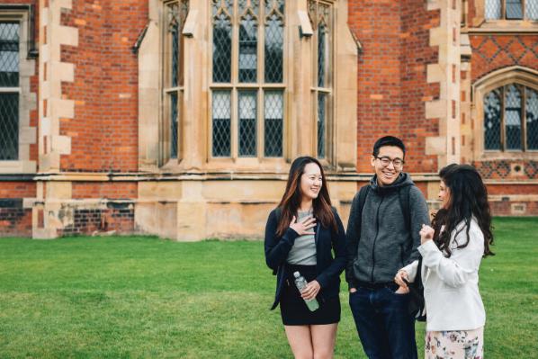 Three students talking and laughing in front of the Lanyon