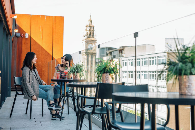 Two students sitting at table on rooftop bar