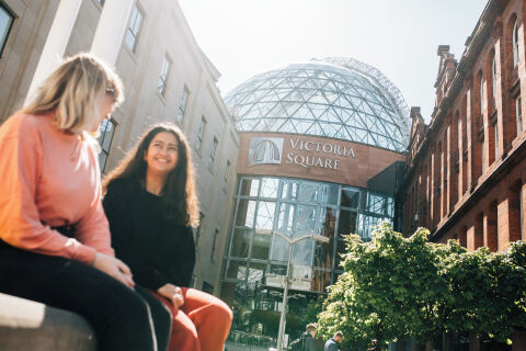 Two students sit outside Victoria Square