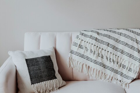 White sofa with white and black throw and cushion on top