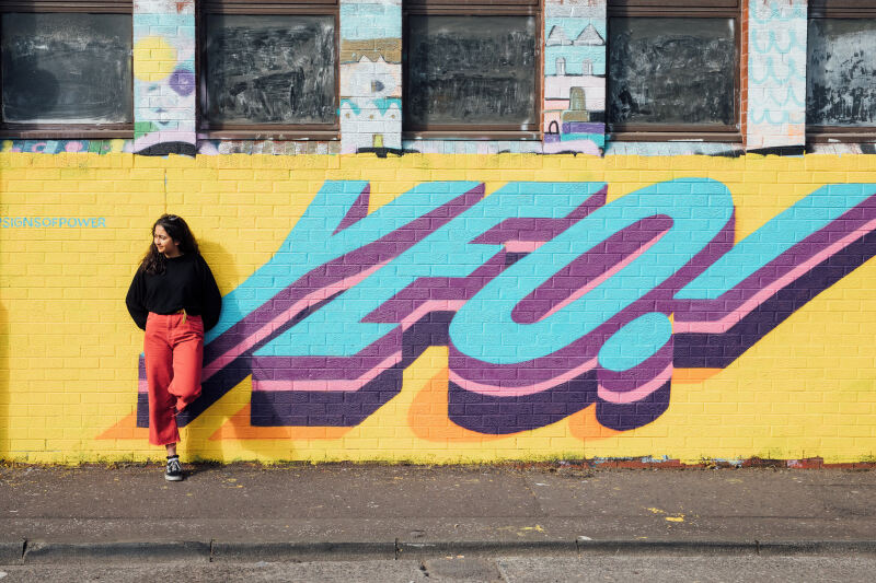 Student standing in front of graffiti in Belfast