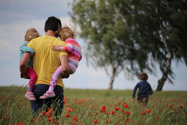 A man carries two children in a field