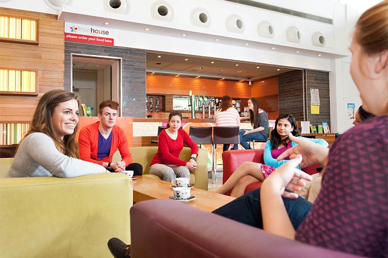 a group of students drinking coffee and relaxing in the Treehouse area of Elm's Village student accommodation