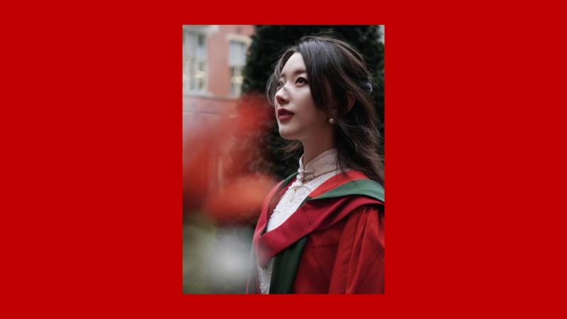 Person wearing graduation gown looking up upwards.