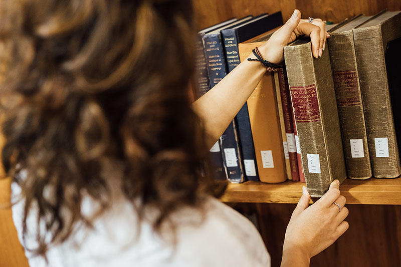 Close up of a student lifting a book in the Special Collections room of The McClay Library