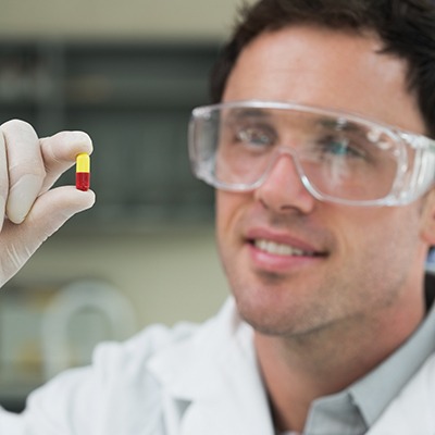 An image of a scientist holding a capsule in a laboratory
