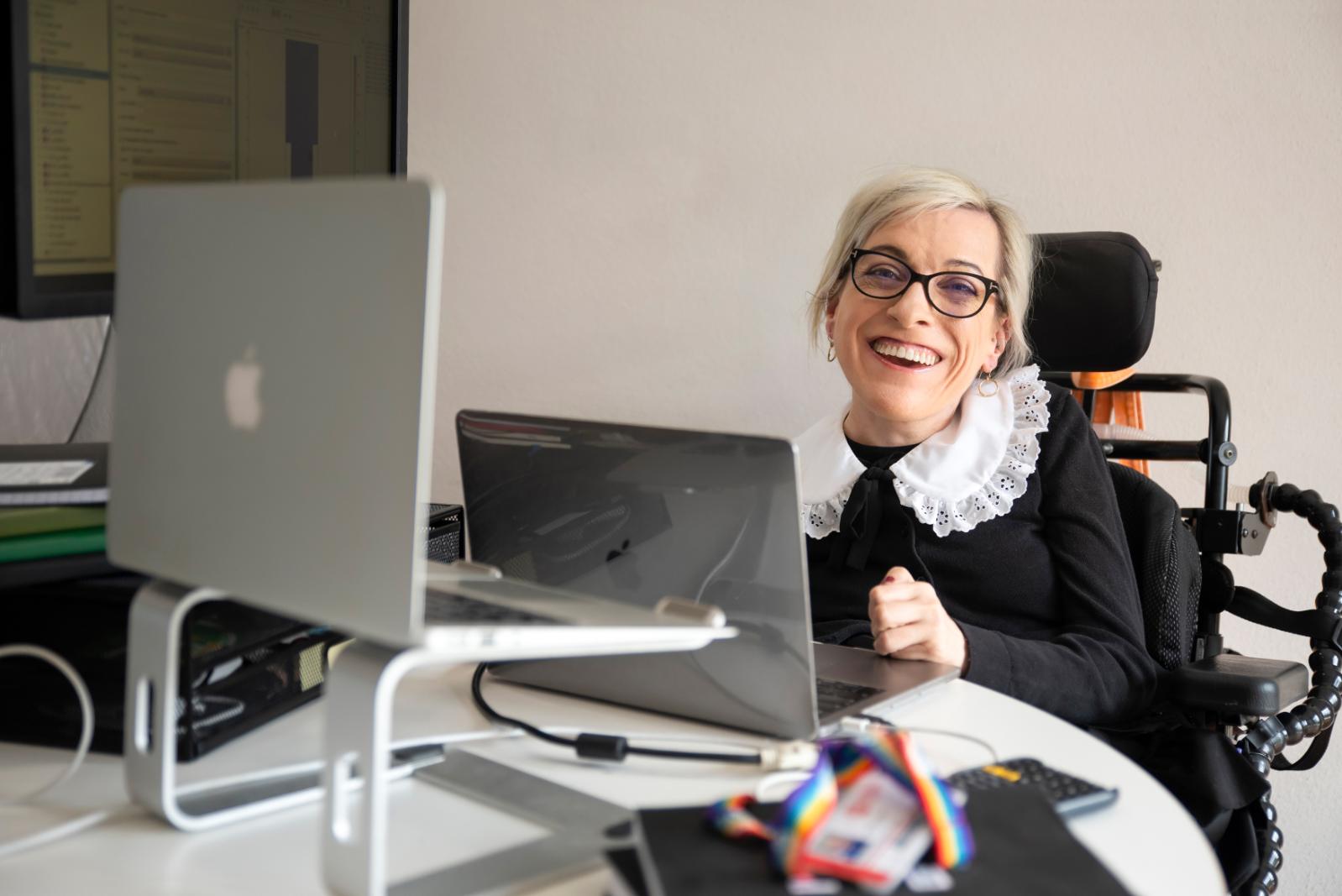 A female student sitting at desk with 2 laptops in front of her