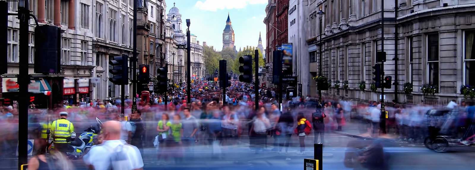 crowd of people in London with Big Ben in the distance and a policeman wearing a hi-vis jacket at the front