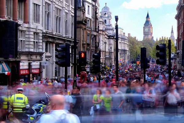 crowd of people in London with Big Ben in the distance and a policeman wearing a hi-vis jacket at the front