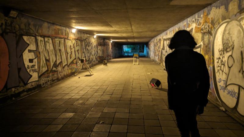 Person standing in a subway with back to camera, looking down the subway