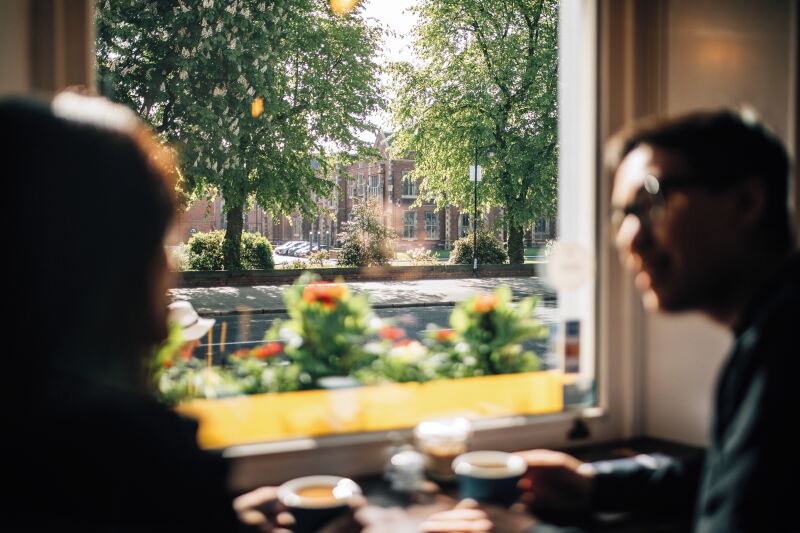 Two students having coffee in cafe in front of the Lanyon