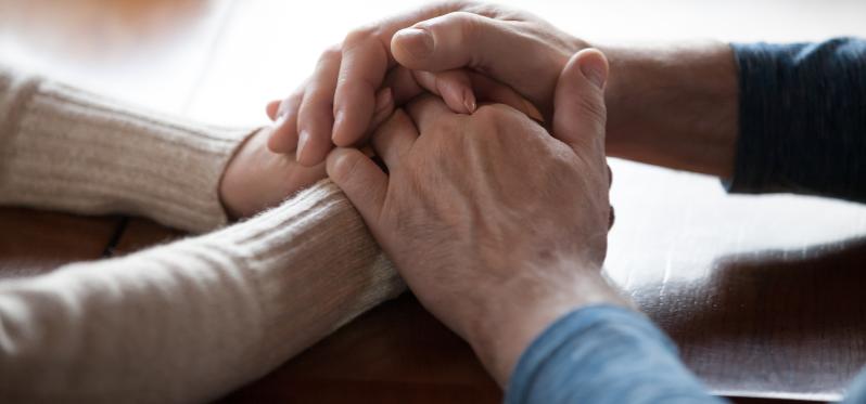 Pair of hands holding each other, one young, one old