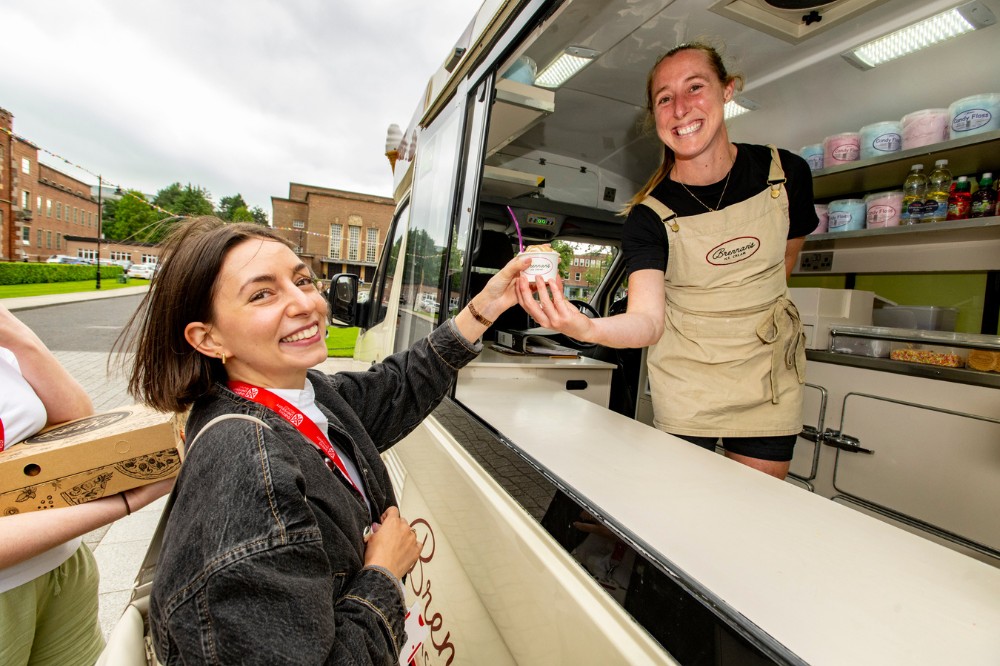 smiling staff member receiving an ice-cream from the ice-cream truck outside Queen's Lanyon Building at the Pride Picnic 2024