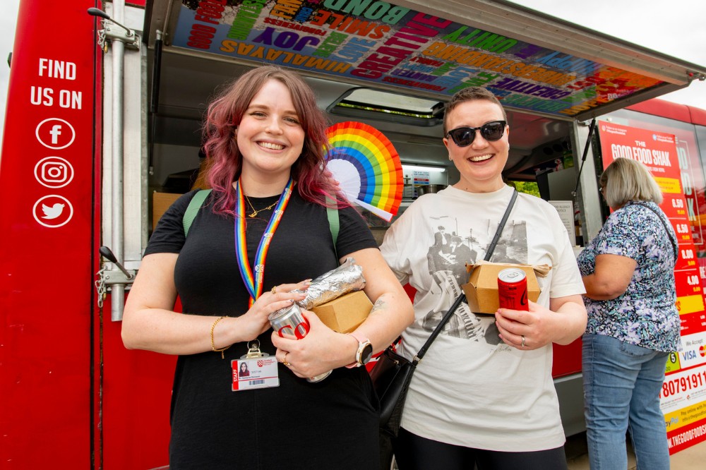 smiling staff member and guest standing beside a food truck at Queen's University Belfast Pride Picnic 2024